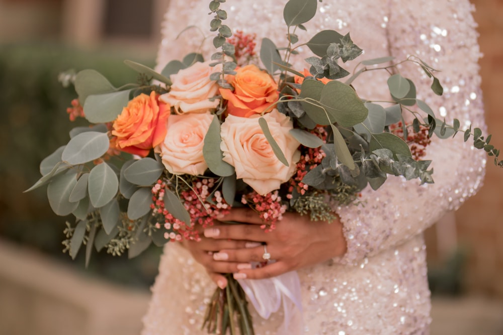 woman in white floral dress holding orange rose bouquet