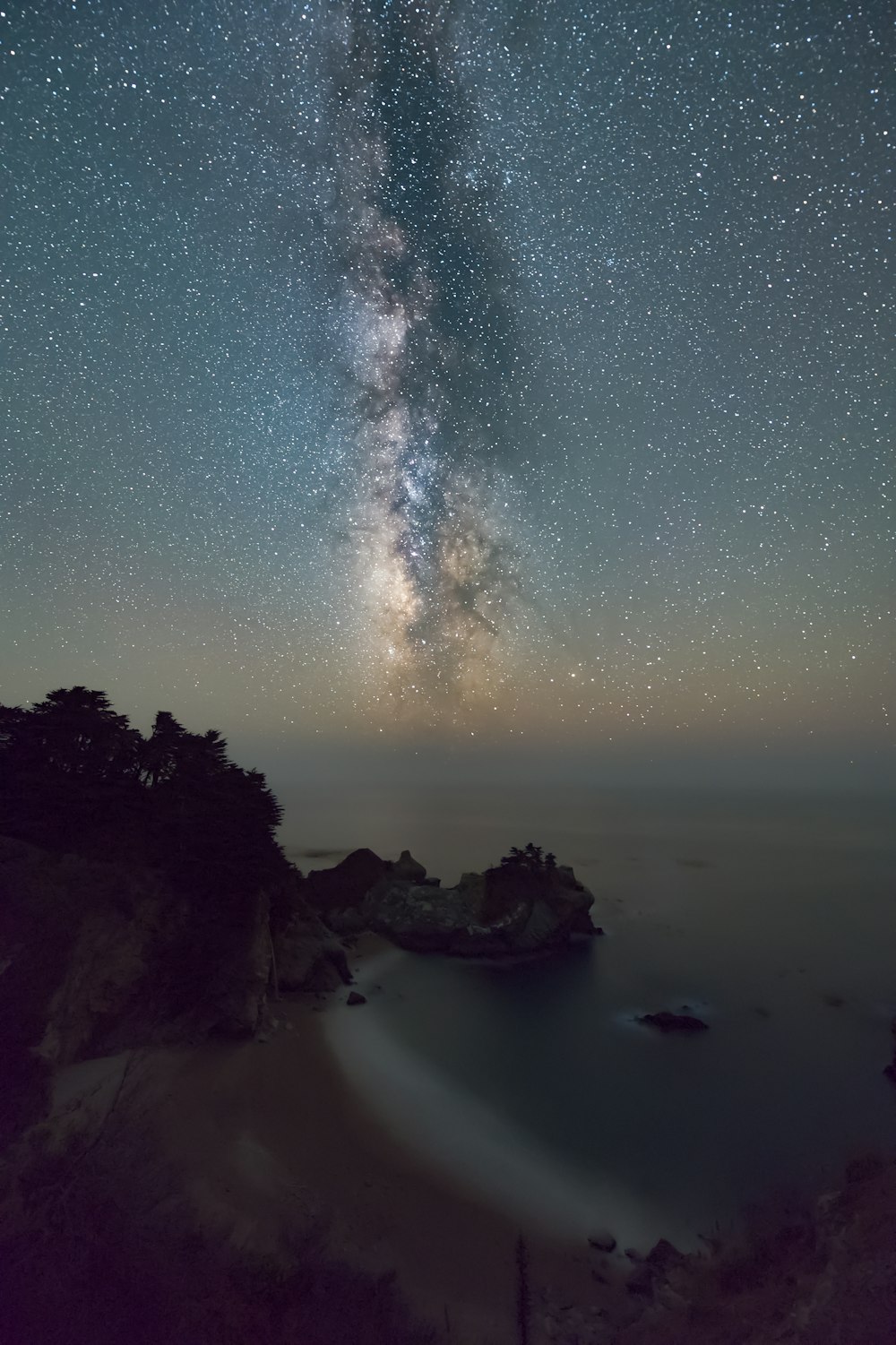 body of water near mountain during night time