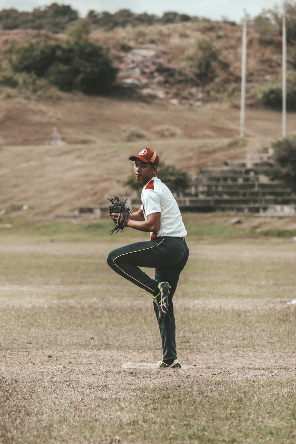 man in white shirt and black pants playing baseball during daytime