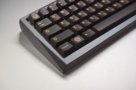 A close-up view of a mechanical keyboard with dark keys featuring Cyrillic letters. The keyboard has a compact layout with a matte finish on its casing.