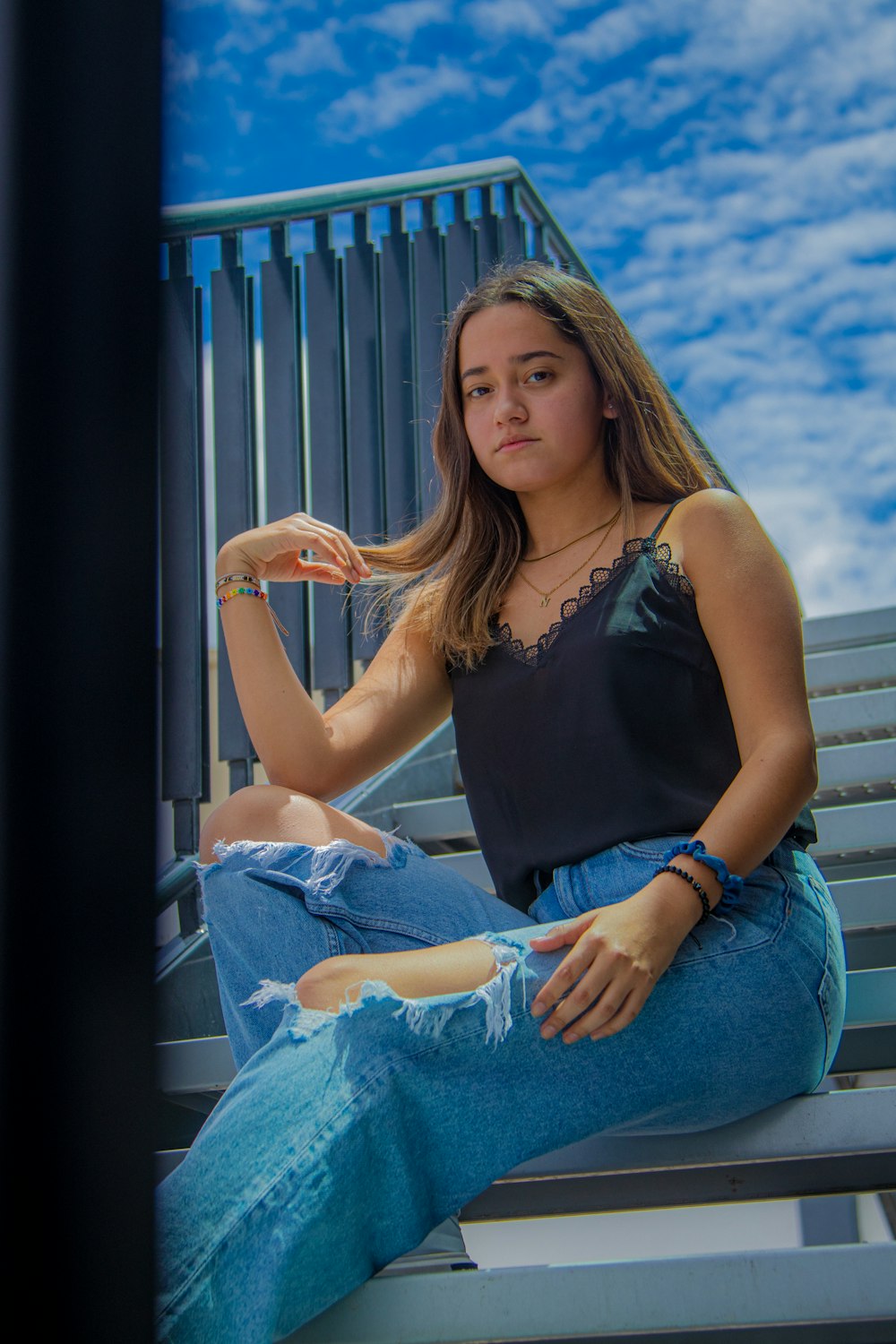 a woman sitting on a bench with her hair in her hand