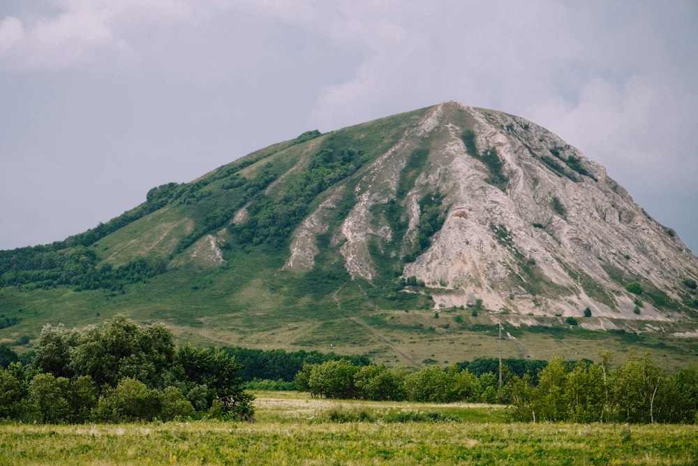 green grass field near mountain under white sky during daytime