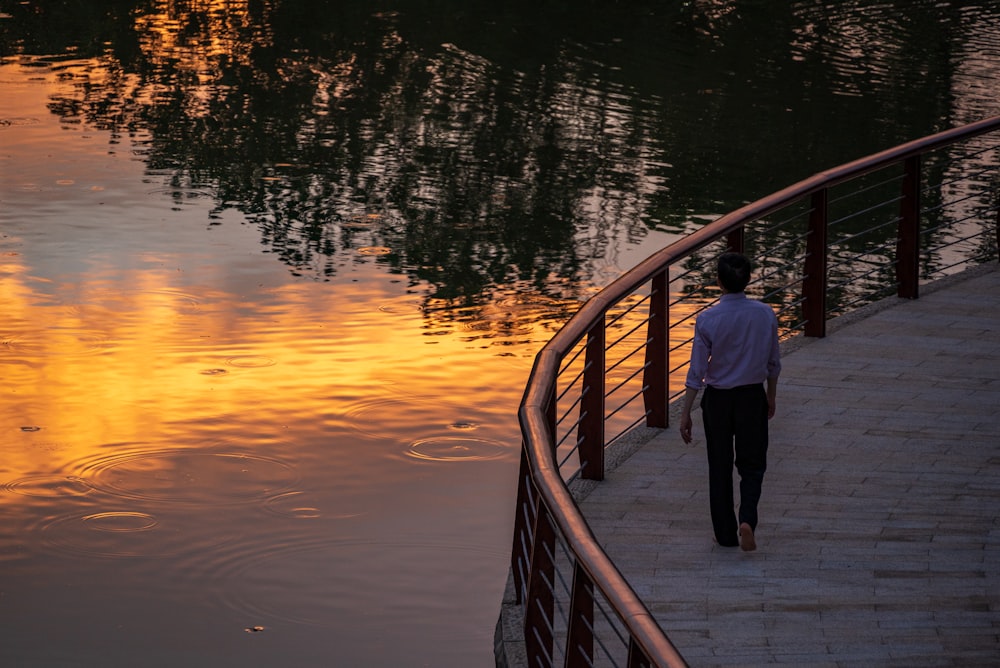 Hombre y mujer de pie en el puente de madera durante la puesta del sol
