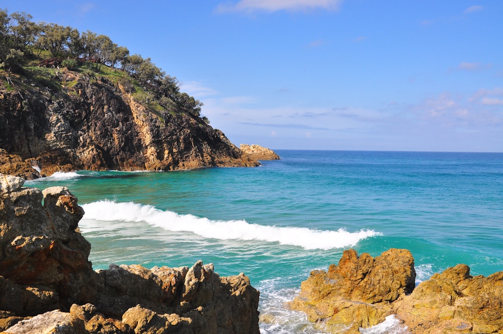 brown rocky mountain beside sea during daytime