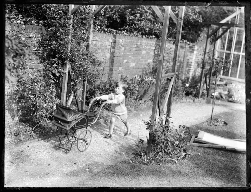 grayscale photo of man sitting on chair near trees