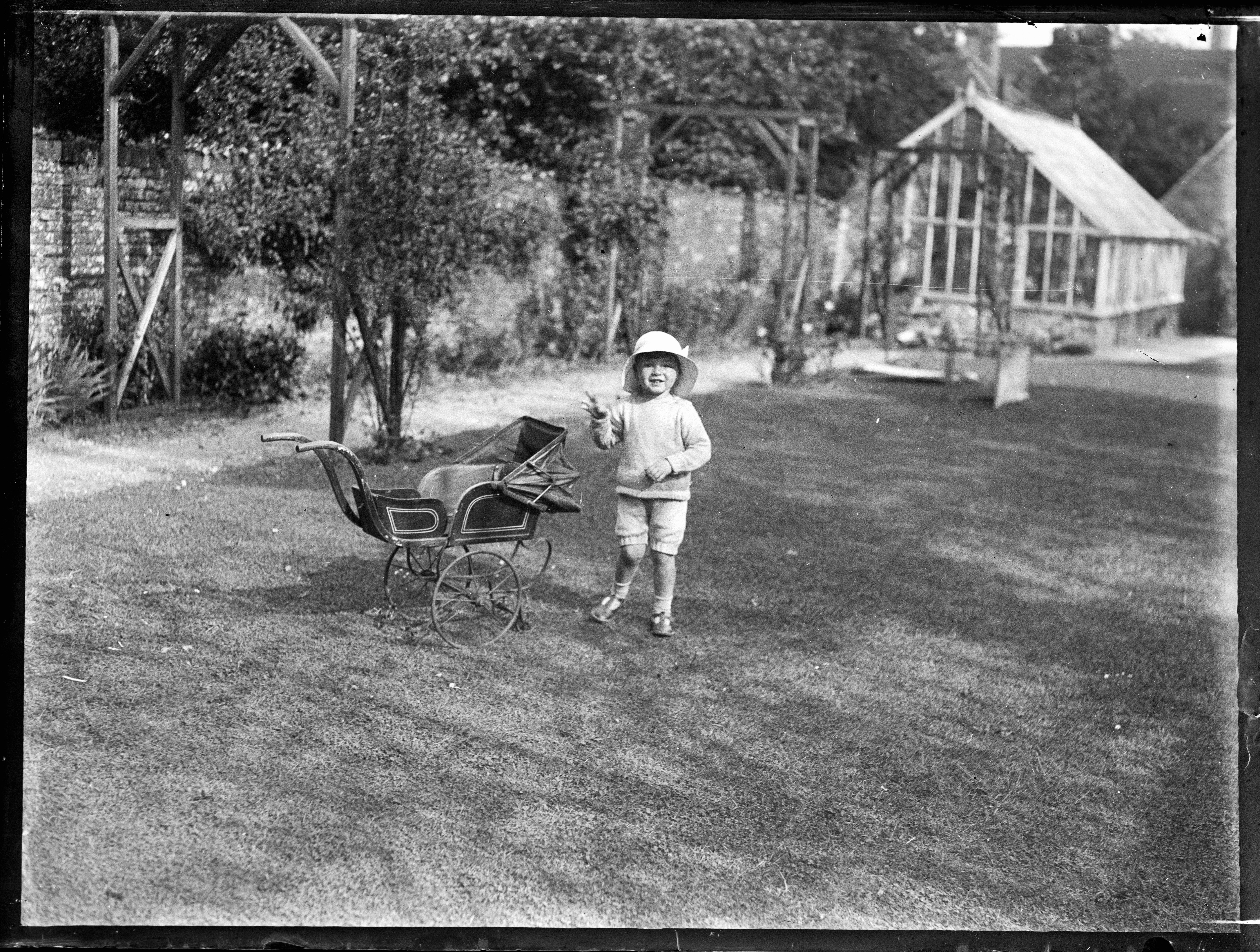 A skeptical boy looking at a potato plant in a garden with his grandmother.