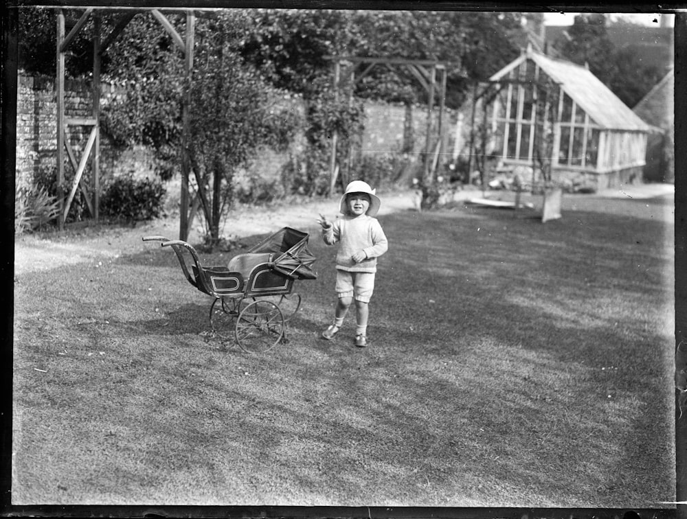 grayscale photo of child walking on grass field