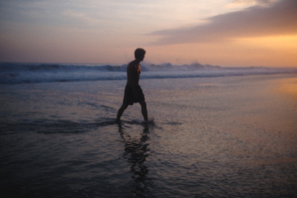 man standing on beach during sunset