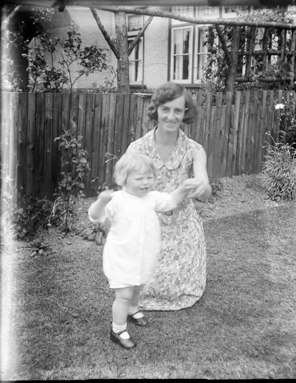 grayscale photo of girl in dress standing on grass field