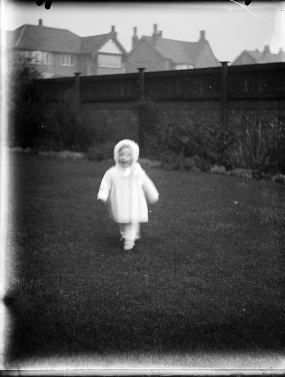 grayscale photo of child in white long sleeve shirt standing on grass field