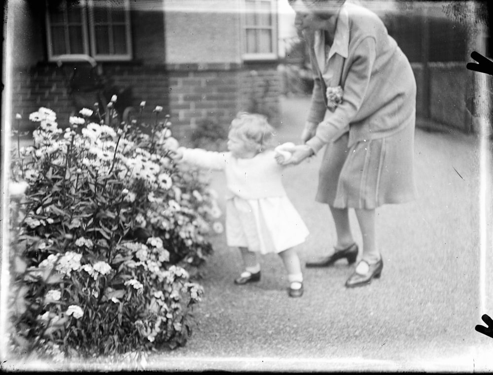 man in gray suit jacket holding baby in white dress