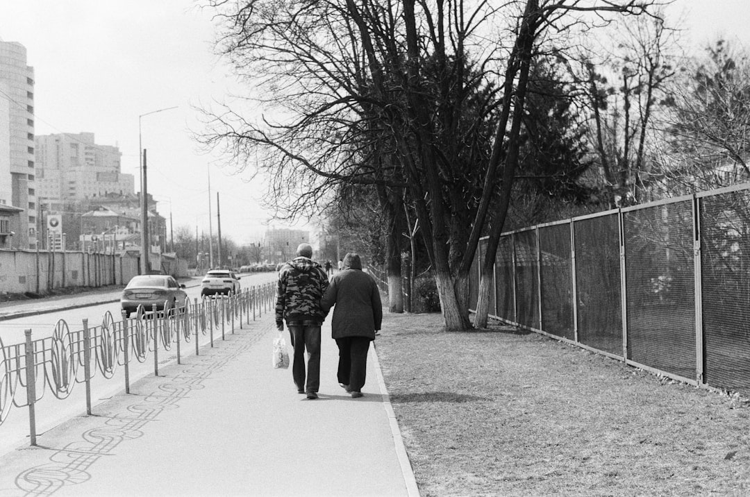 grayscale photo of man and woman walking on sidewalk