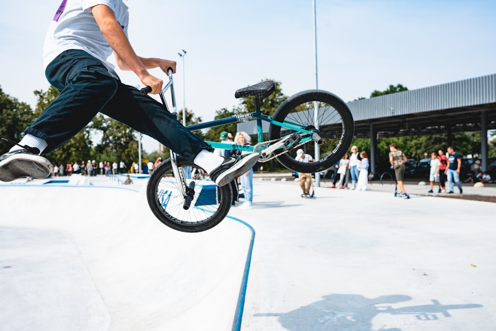 白いTシャツを着た男が日中にスタントをするBMXバイクに乗る