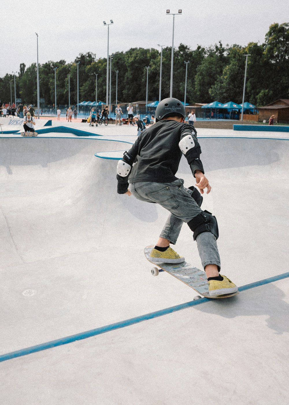 Hombre con chaqueta negra y pantalones negros montando en una tabla de snowboard azul y blanca