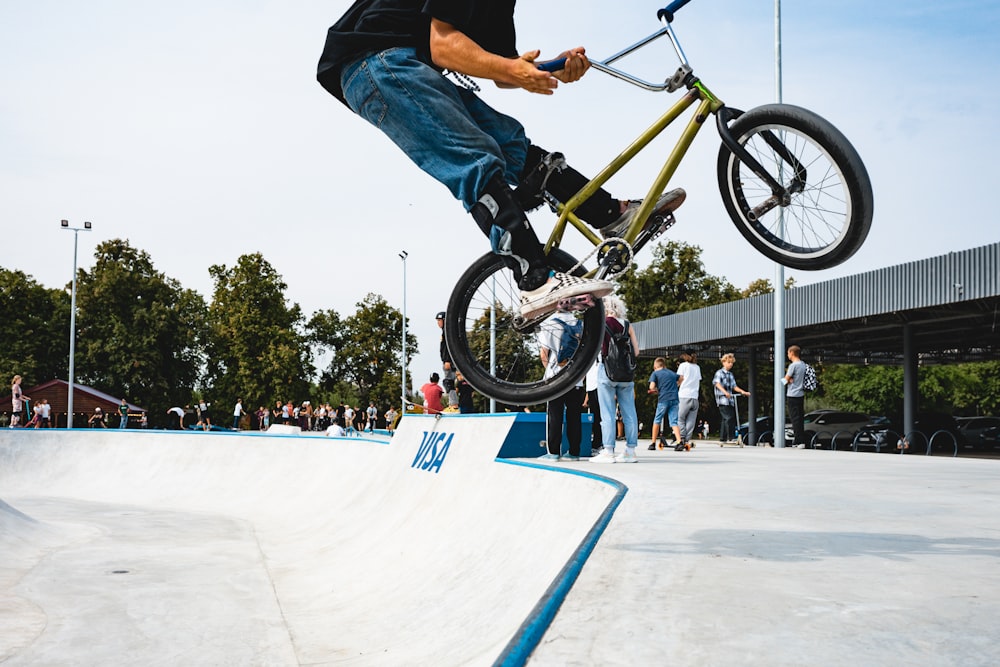 homem em jeans azuis que montam na bicicleta amarela da bmx