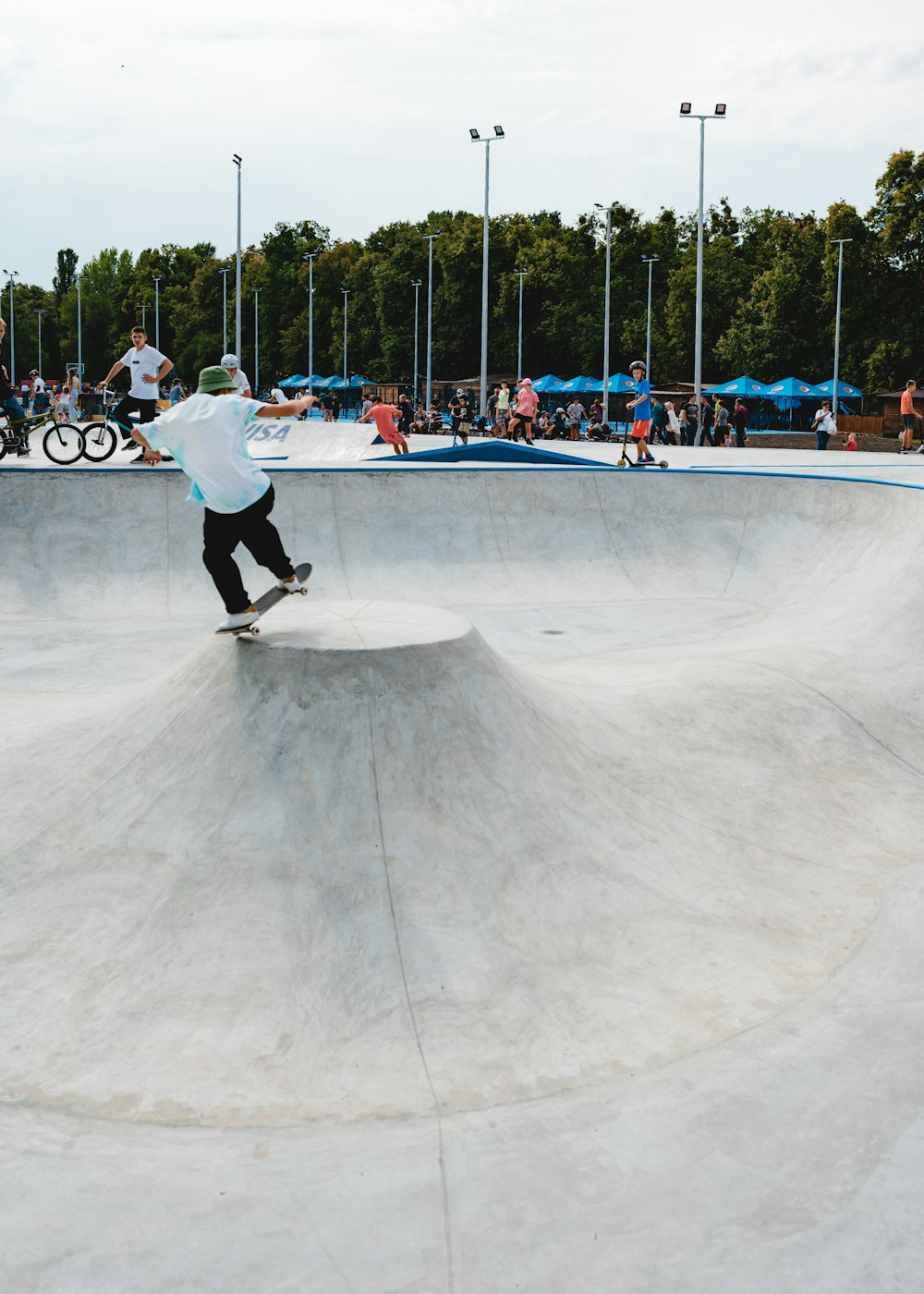 uomo in camicia bianca a maniche lunghe e pantaloni neri che gioca skateboard durante il giorno