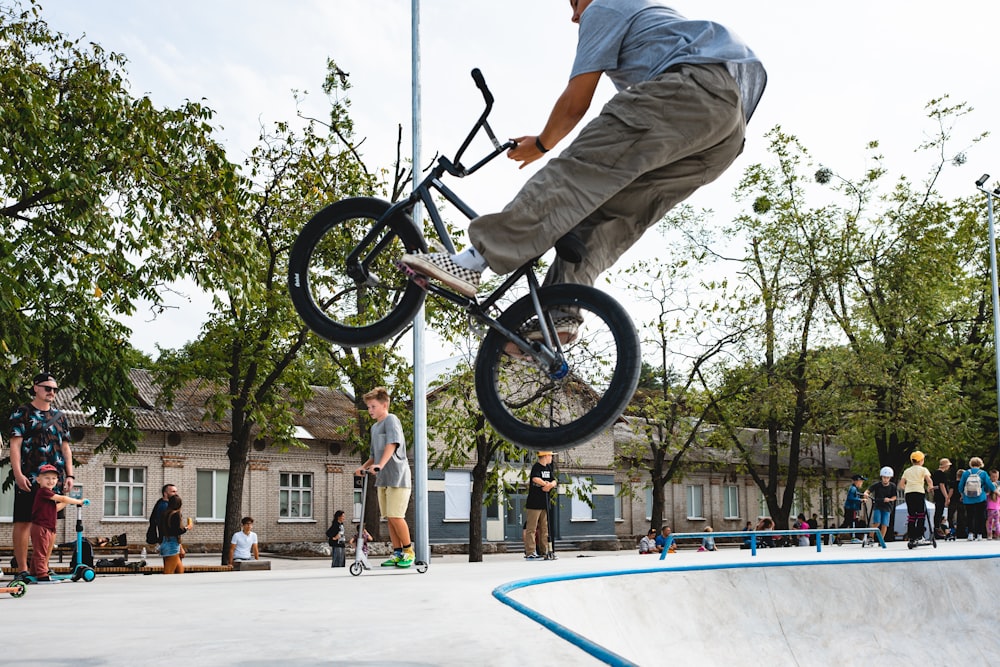 man in gray shirt riding on black bmx bike doing stunts during daytime