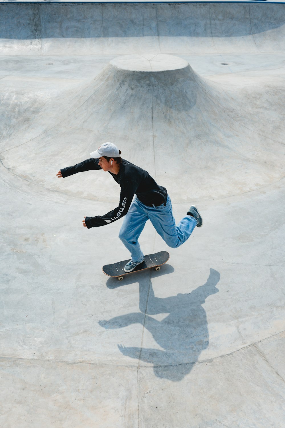 Mann in schwarzer Jacke und blauer Jeans auf Skateboard