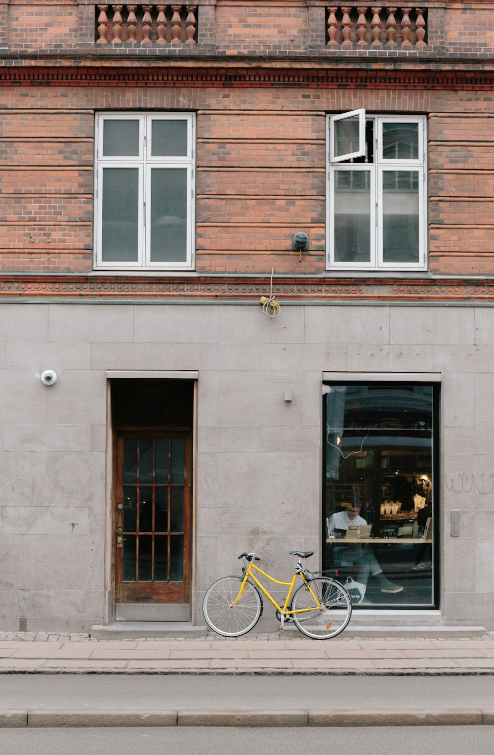 yellow city bike parked beside brown concrete building during daytime