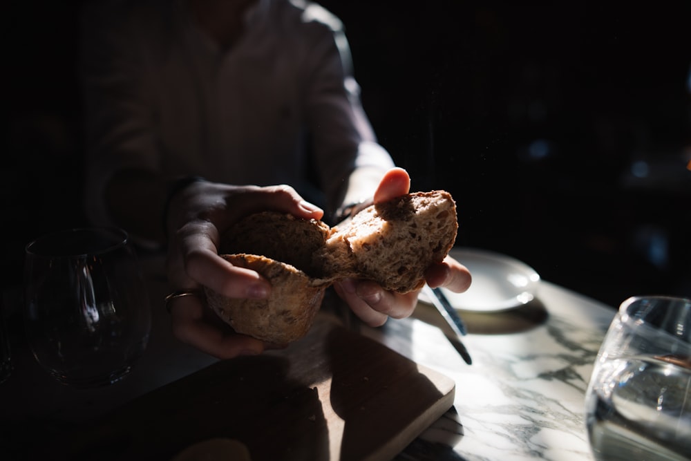 person in white dress shirt holding bread