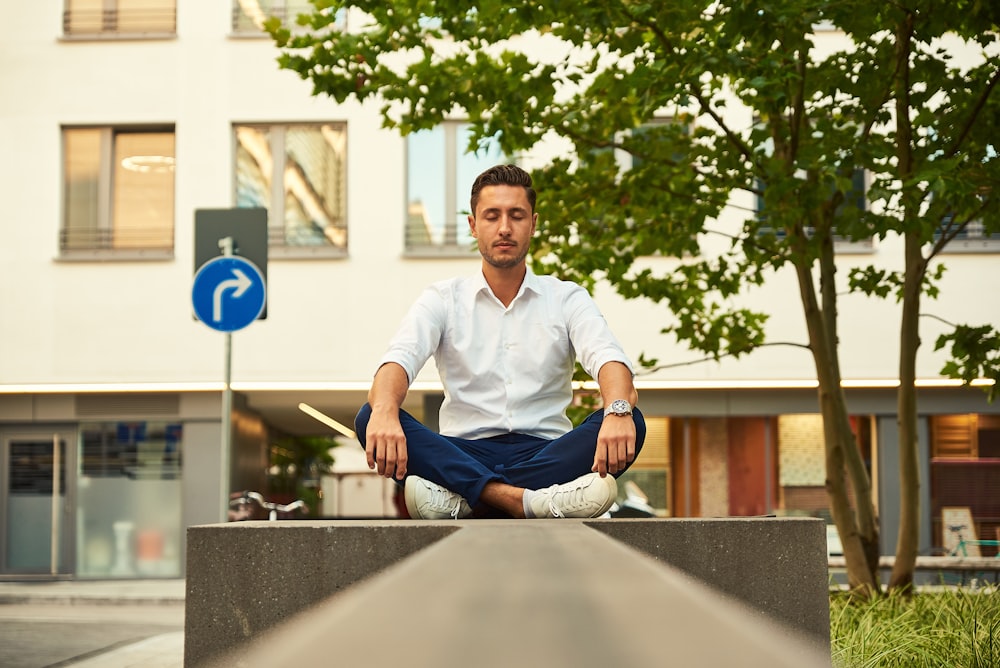 man in white dress shirt sitting on gray concrete bench during daytime