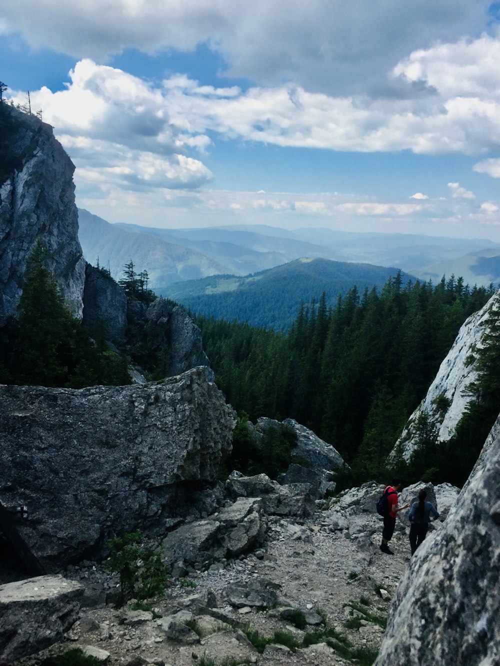 person in red jacket standing on rocky mountain during daytime