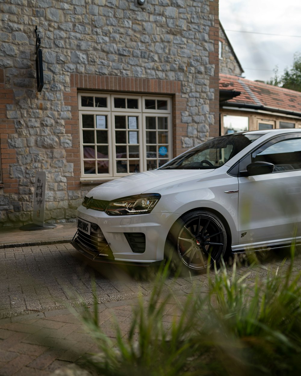 silver car parked beside brown brick wall