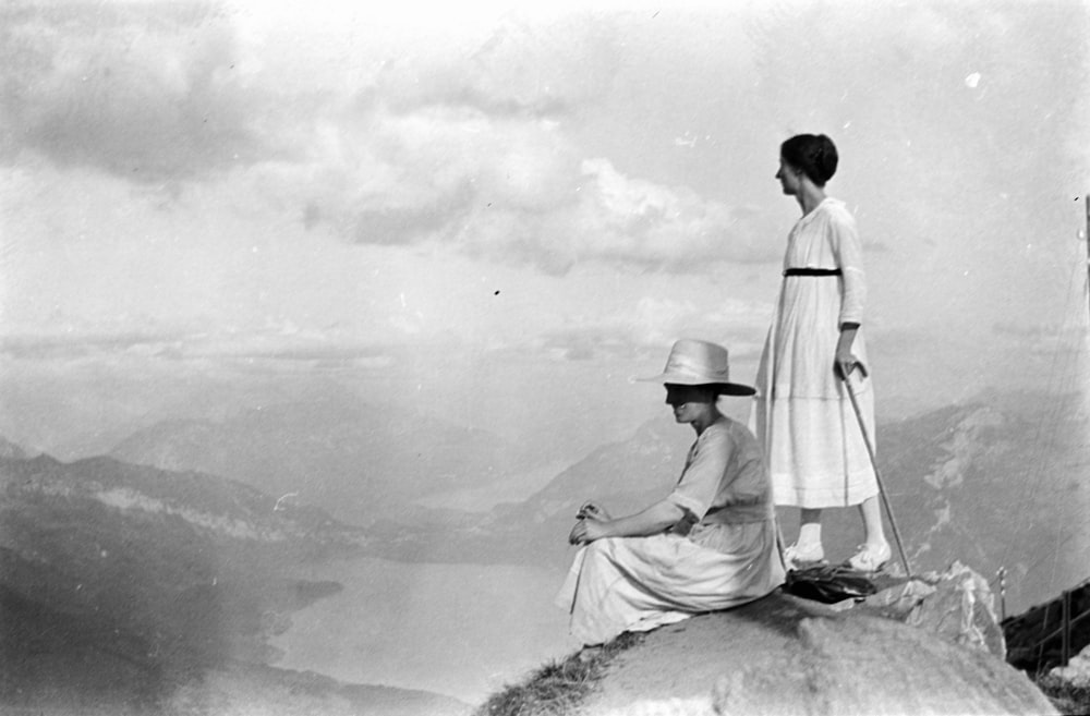 man and woman standing on rock in grayscale photography