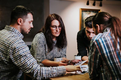 Four people reviewing documents at a wooden table in a workspace