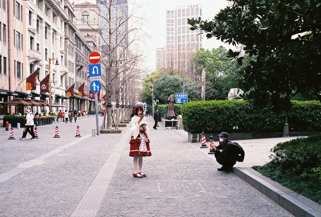 woman in red and white dress walking on sidewalk during daytime