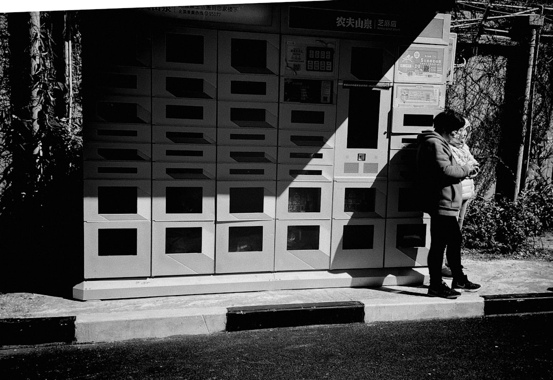 man in black jacket and pants standing beside white and black building