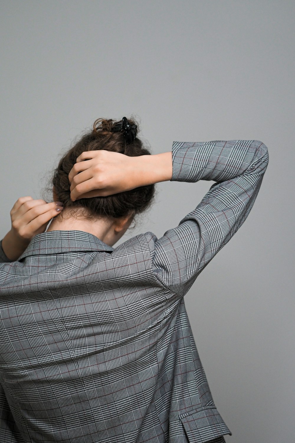 woman in gray and white plaid long sleeve shirt covering her face with her hair