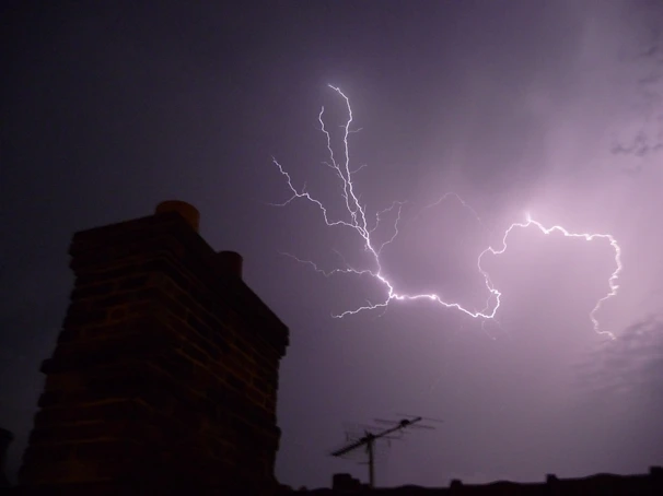 Close-up of a digital lightning strike counter installed on a rooftop under a clear sky.