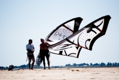 man and woman standing on brown sand near white and black ship during daytime