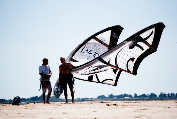man and woman standing on brown sand near white and black ship during daytime