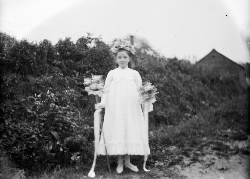 Mädchen in weißem Kleid mit Blumenstrauß
