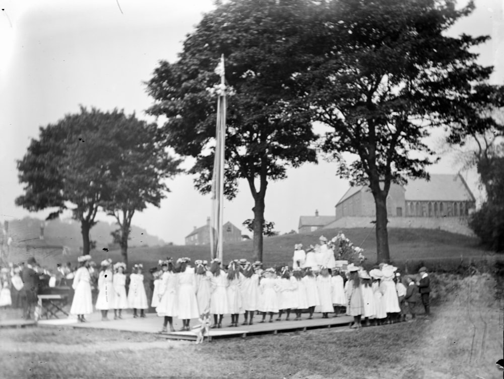 grayscale photo of people standing near trees