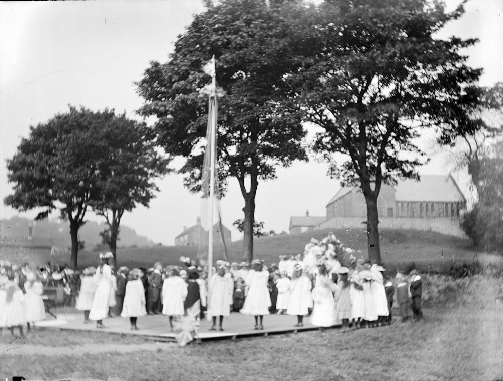 grayscale photo of people standing near trees