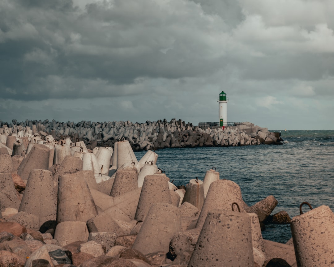 white and black lighthouse near body of water under cloudy sky during daytime