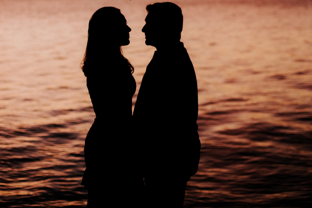 silhouette of couple standing on beach during sunset