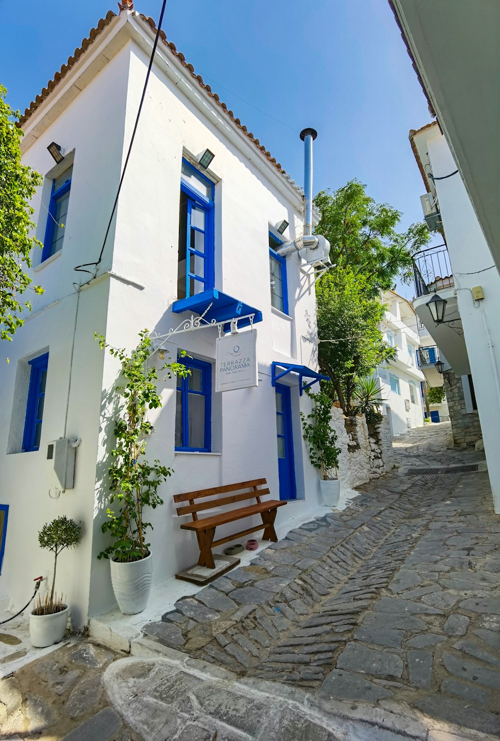 brown wooden bench beside white concrete building during daytime