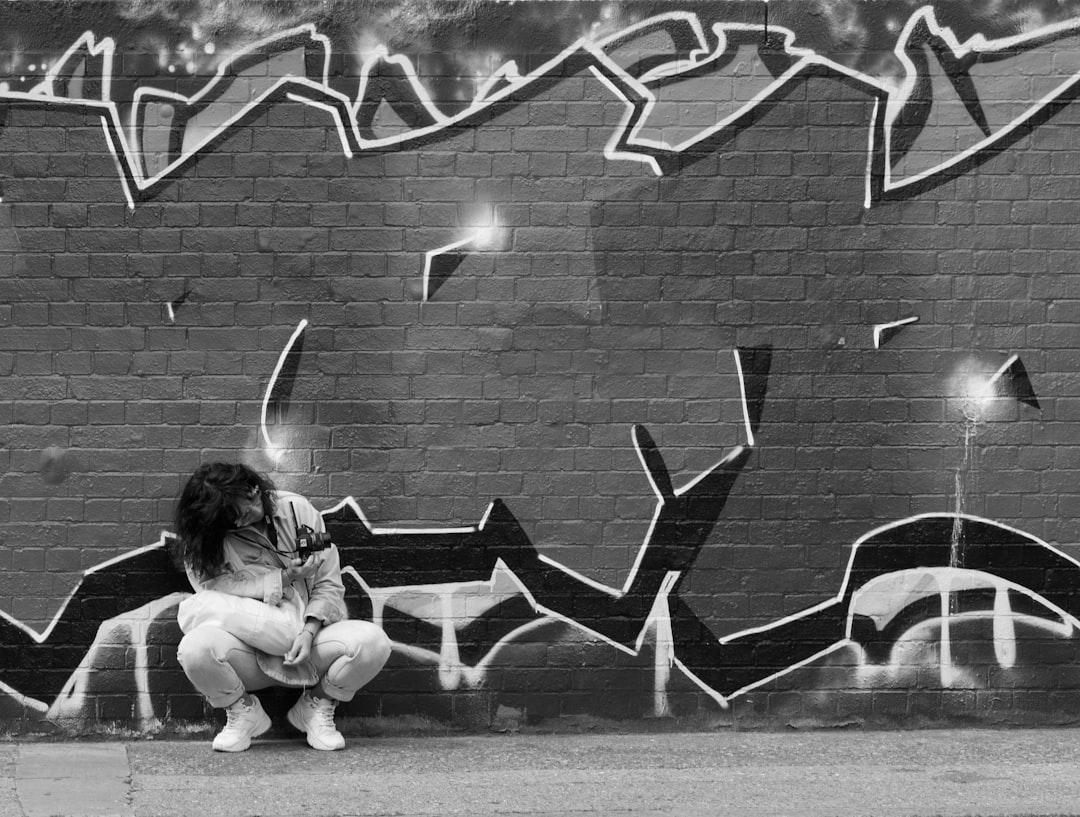 girl sitting on bench near wall with graffiti,