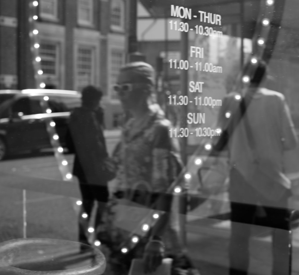 grayscale photo of man and woman standing near glass wall