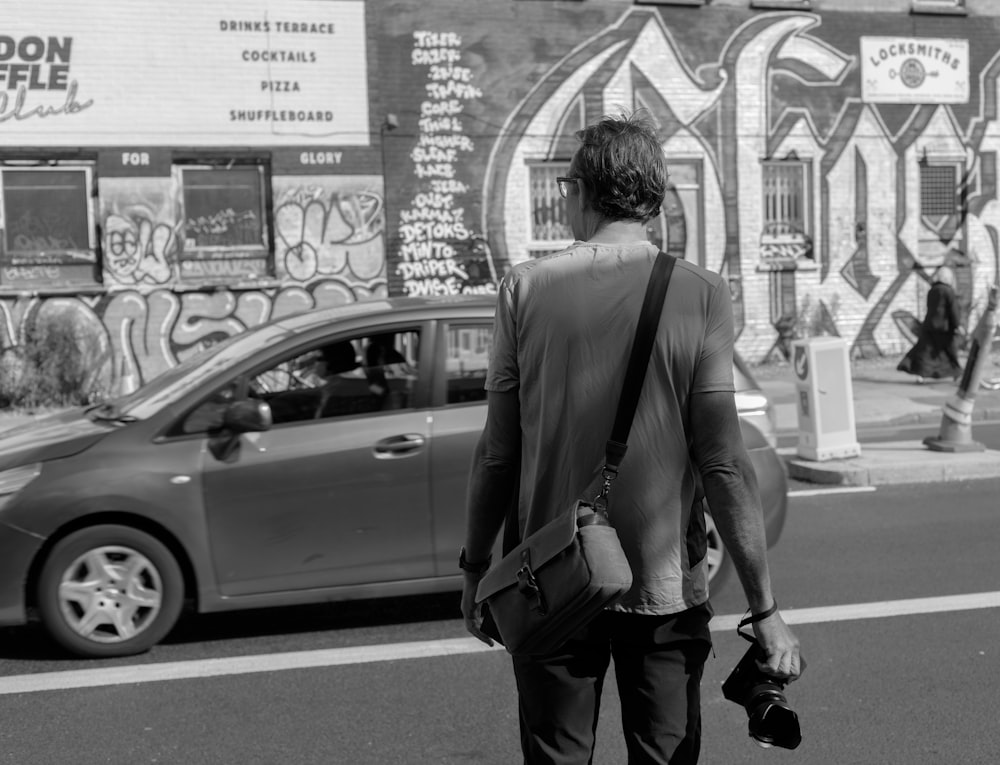 grayscale photo of woman in black jacket and black pants standing on sidewalk