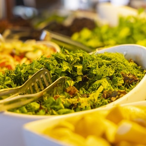 yellow pasta with green leaves in white ceramic bowl