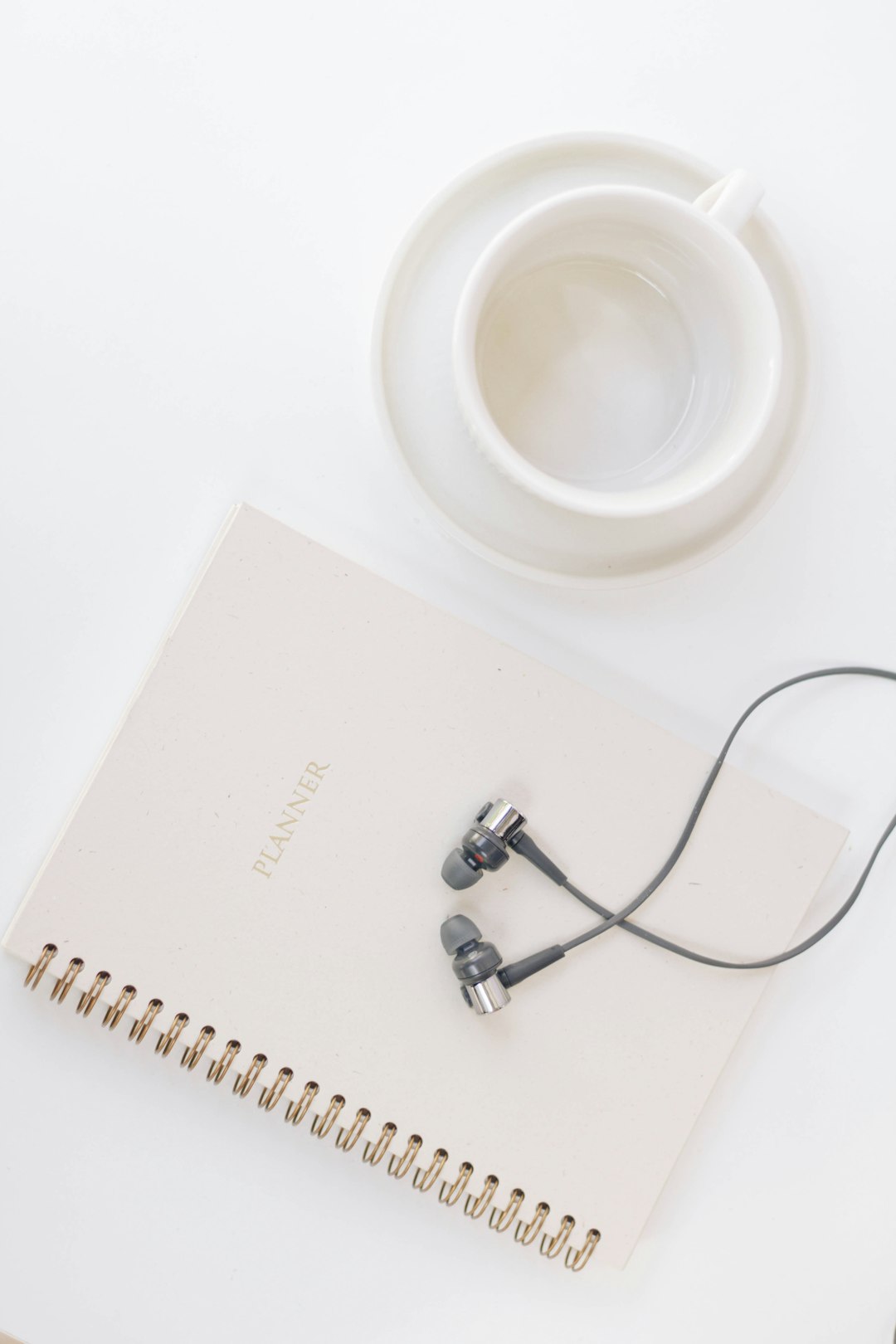 white spiral notebook beside white ceramic mug