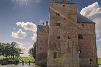 Players collaborating on a large Minecraft castle under a bright blue sky.