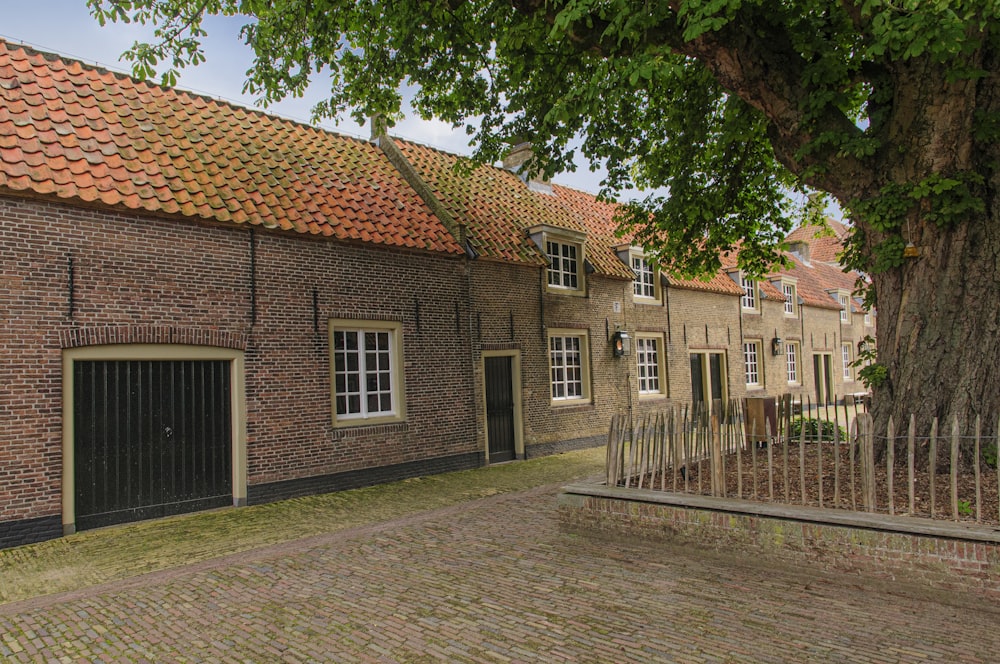 brown brick house near green trees during daytime