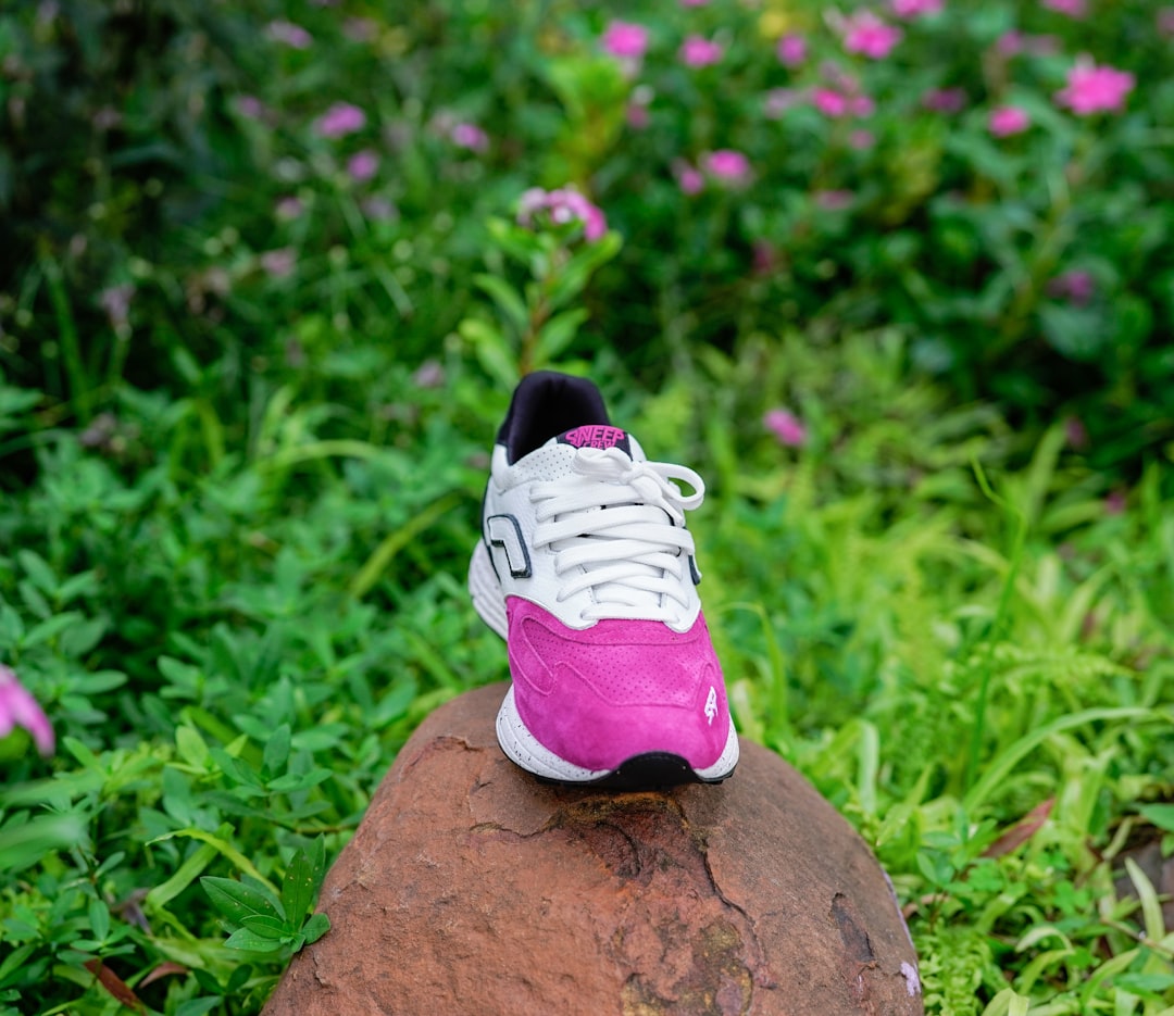 white and pink nike shoe on brown rock