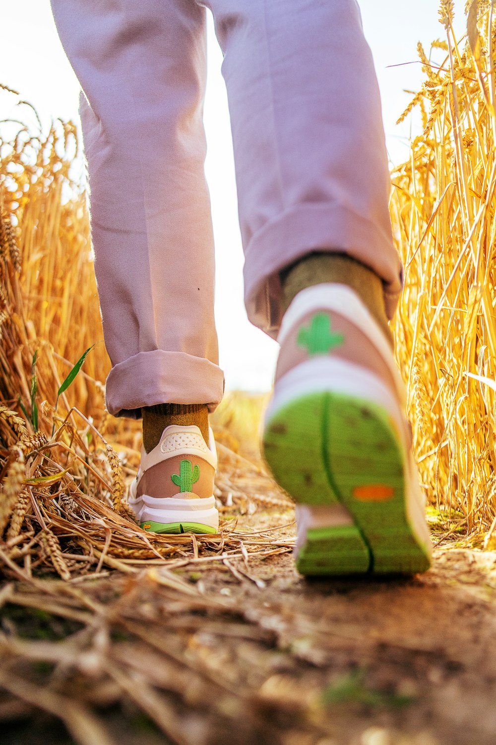 person in blue denim jeans and white sneakers standing on brown grass field